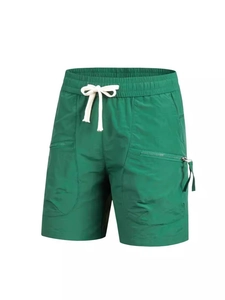 Detail of green quick-dry sports shorts with white drawstring and large side zipper pockets