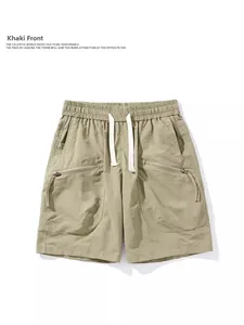Detail view of khaki cargo shorts featuring elastic waistband and functional zip pockets