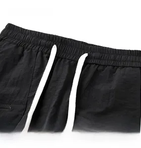 Detail view of elastic waistband with adjustable white drawstring on black cargo shorts
