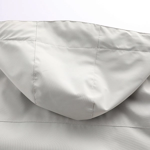 Detail of hood stitching and windproof fabric on a light gray outdoor parka jacket