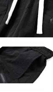 Detail der schwarzen Cargo-Shorts mit weißen geflochtenen Kordelzügen und Reißverschlusstaschen