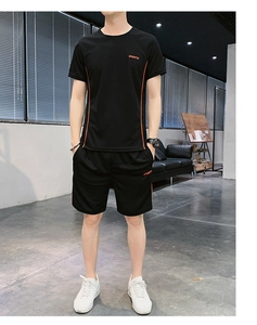 Détail d'un ensemble sport noir homme avec bandes orange et texte SPORTS imprimé en rouge