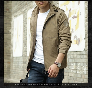 Detail of khaki outdoor jacket showing embroidered sleeve badge and hooded collar design
