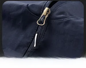 Detailed close-up of a durable bronze metal zipper on a dark blue men's utility vest