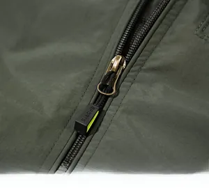 Detail of durable metal zipper with SPORTS pull tab on green outdoor jacket