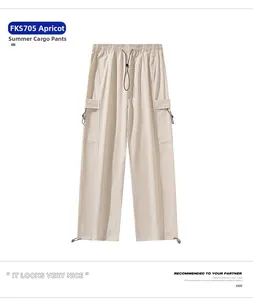 Detail view of apricot techwear parachute pants with functional drawstring and utility pockets