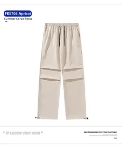 Detail view of apricot techwear parachute pants with drawstring waist and cargo pockets