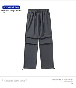Detail of loose fit dark grey parachute pants featuring cargo pockets and drawstring cuffs