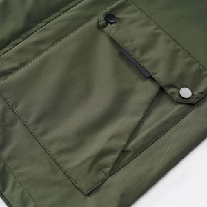 Detail of army green windproof jacket showing a flap pocket with two black metal snap buttons