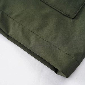 Macro shot of high-quality stitching and olive green durable woven fabric on the jacket