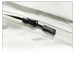 Dettaglio macro della cerniera in metallo nero sul tessuto beige del gilet esterno