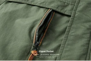 Detail view of military green jacket showing a zipper pocket with brown leather pull tab