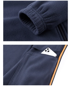 Détails de la veste polaire avec poignets élastiques, poches profondes et bordure orange