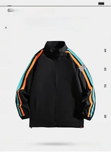 Détail de la manche d'une veste noire avec rayures bleu-orange et étiquette SPORT