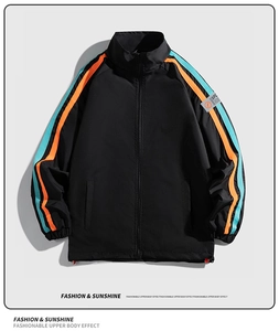 Détail d'une veste de sport noire avec bandes latérales orange et bleu clair et cordon de serrage