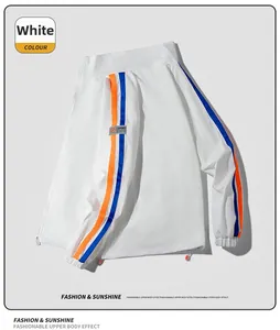 Détail de la veste de sport blanche avec bandes de manches orange-bleu et poignets