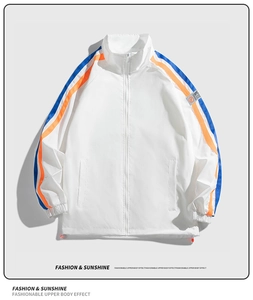 Détail de la veste de sport blanche à col montant avec rayures bleues et orange et écusson