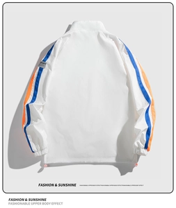 Détail de la veste de sport blanche montrant des bandes bleu et orange avec label SPORT