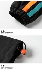 Détail de la veste noire coupe-vent avec rayures bleu et orange et cordon de serrage