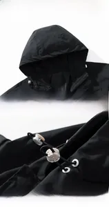 Close-up detail of integrated hood and adjustable drawstring system on black jacket
