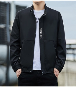 Detail der schwarzen Stehkragenjacke mit Metallreißverschluss und weißem Buchstabendruck