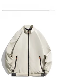 Detail view of beige stand-up collar jacket with orange zipper pulls and ribbed cuffs