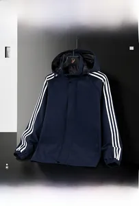 Detailed view of elastic cuffs and white triple stripes on navy blue windbreaker jacket