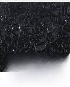 Vue détaillée du tissu imperméable à motif de palmes avec des gouttes d'eau hydrophobes