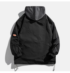 Détail d'une veste coupe-vent avec écusson orange et capuche grise en vue arrière