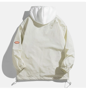 Detail view of the back of a beige hooded jacket with an orange logo patch on the sleeve