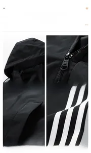 Detail view of black hooded jacket with three white stripes on sleeve and metal zipper