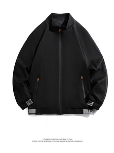 Close-up of black jacket zipper with orange U-puller and grey ribbed lettered cuffs