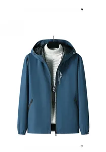 Détail d'un coupe-vent à capuche bleu denim avec logo montagne et poches zippées