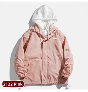 Détail de veste à capuche rose et blanche avec écusson orange et poignets élastiques