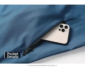 Détail d'une veste outdoor imperméable montrant une poche zippée profonde et un mobile