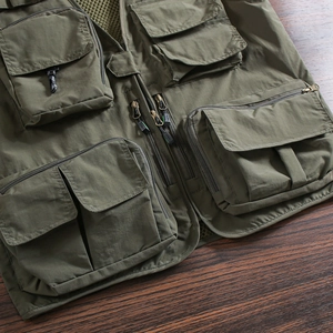 Detailed view of army green tactical vest featuring multiple functional utility pockets