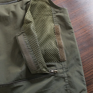 Detail of military green tactical vest showing mesh lining and durable cargo pocket