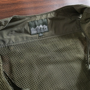 Detail of army green fishing vest featuring breathable honeycomb mesh lining and outdoor label