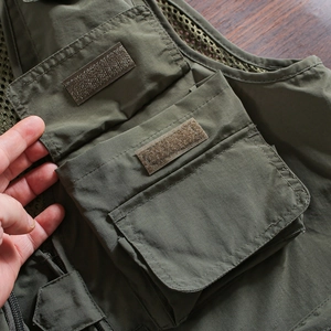 Detail of military green tactical vest featuring large 3D pockets with velcro closures