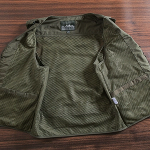 Detail view of military green outdoor vest featuring breathable mesh fabric and size label