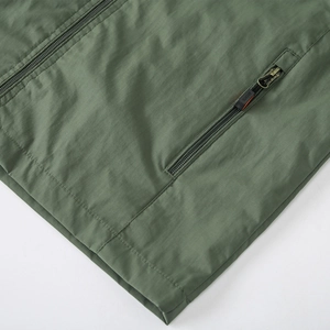 Detail view of dark green hiking jacket featuring smooth zipper and sports pocket