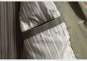 Detail of army green jacket interior featuring striped lining and reinforced inner pocket