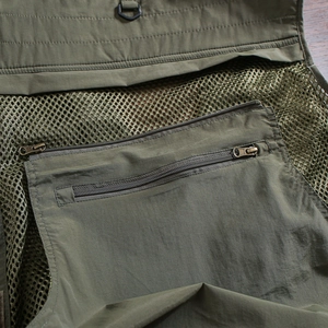 Detail of large rear zipper pocket and breathable mesh on army green fishing vest