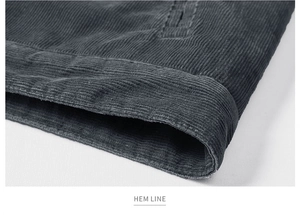 Macro shot of dark grey corduroy jacket hem showing ribbed texture and neat stitching