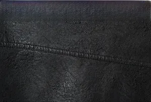 Dettaglio macro della texture in pelle della giacca moto con cuciture premium e artigianali