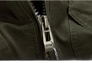 Detail shot of the vintage bronze metal zipper with H.T.N engraving on green canvas jacket
