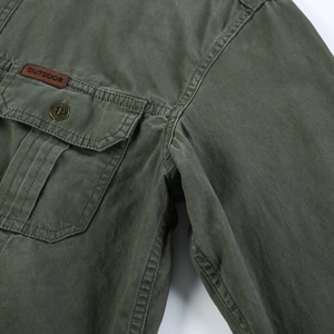 Détail de la veste en coton olive montrant la poche de poitrine avec bouton et étiquette cuir
