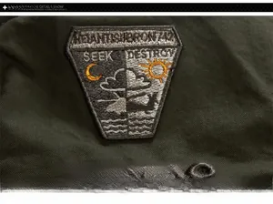 Detail of embroidered patch and military letters on dark green flight jacket fabric