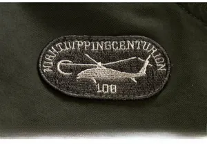 Detail shot of embroidered helicopter badge and fabric texture on green flight jacket