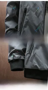 Detail der grauen Herrenjacke mit Buchstabendruck, Reißverschlusstaschen und Windschutzbündchen